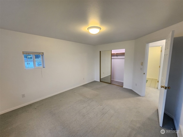 unfurnished bedroom featuring light carpet and a closet