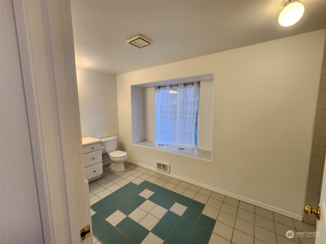 bathroom with toilet, vanity, and tile patterned flooring