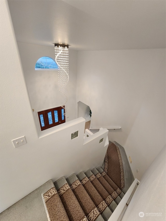 stairway with carpet flooring and an inviting chandelier