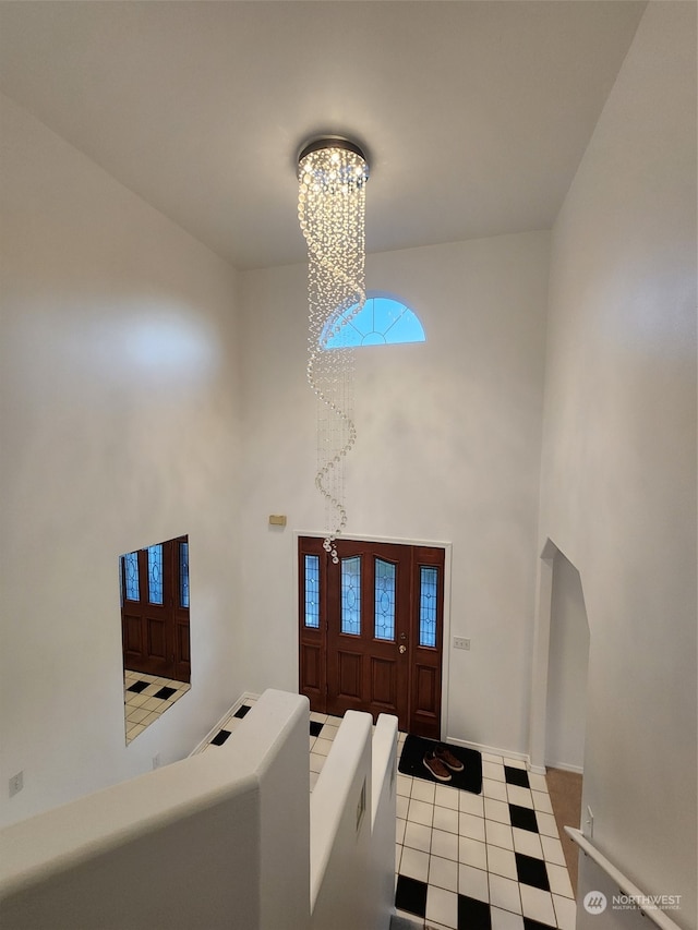 tiled foyer entrance with a high ceiling and a notable chandelier