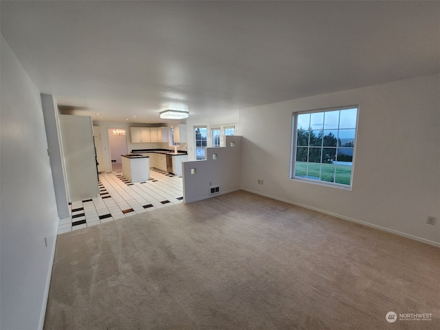 unfurnished living room featuring light carpet and plenty of natural light