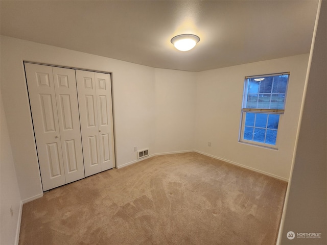 unfurnished bedroom featuring light carpet and a closet