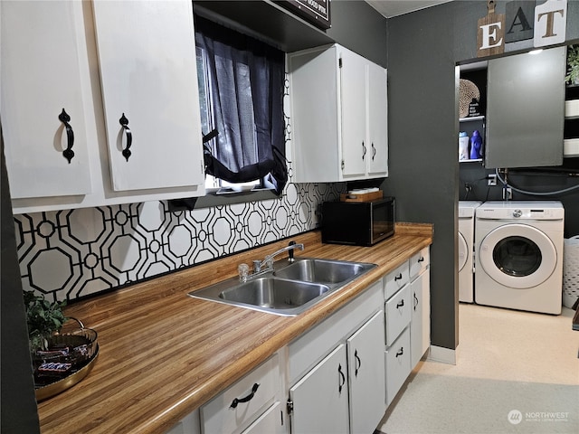 kitchen with sink, white cabinetry, washing machine and clothes dryer, and backsplash