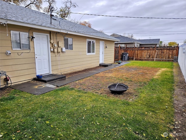 rear view of property with a lawn and a fire pit