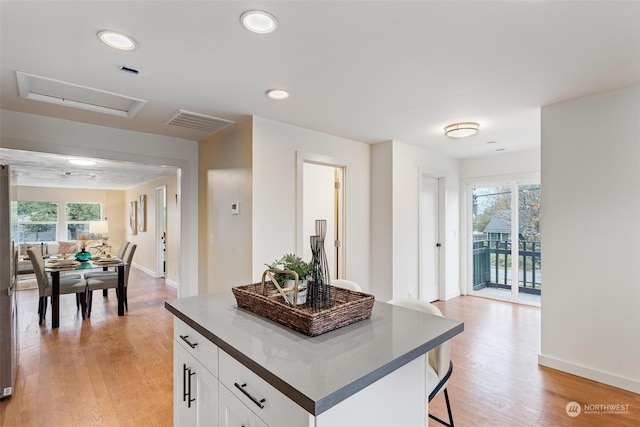 kitchen featuring a kitchen island, white cabinetry, light wood-type flooring, and plenty of natural light