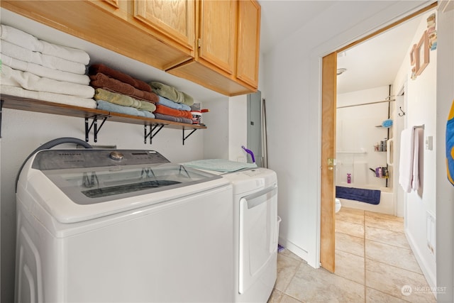 clothes washing area with light tile patterned floors, cabinets, and washer and dryer