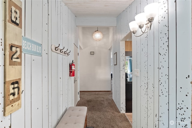 hallway featuring wood walls and light colored carpet