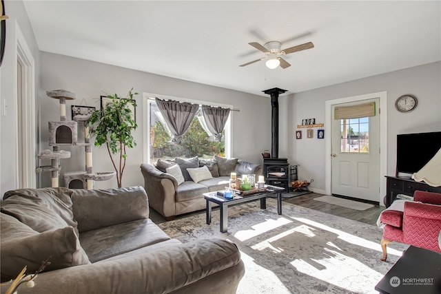 living room featuring a wood stove, ceiling fan, and light hardwood / wood-style floors