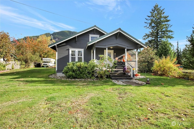 view of front of home with a mountain view, a front lawn, and covered porch