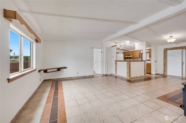 unfurnished room with a textured ceiling, lofted ceiling with beams, and light tile patterned floors