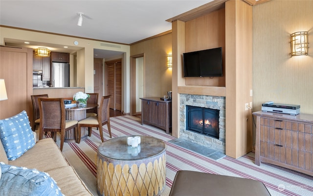 living room with a stone fireplace, crown molding, and light colored carpet