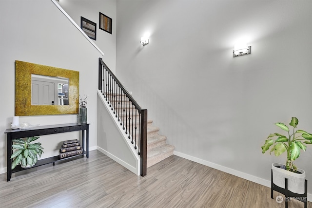 staircase with wood-type flooring and a high ceiling