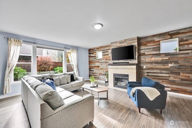 living room with hardwood / wood-style flooring, a tile fireplace, and wood walls