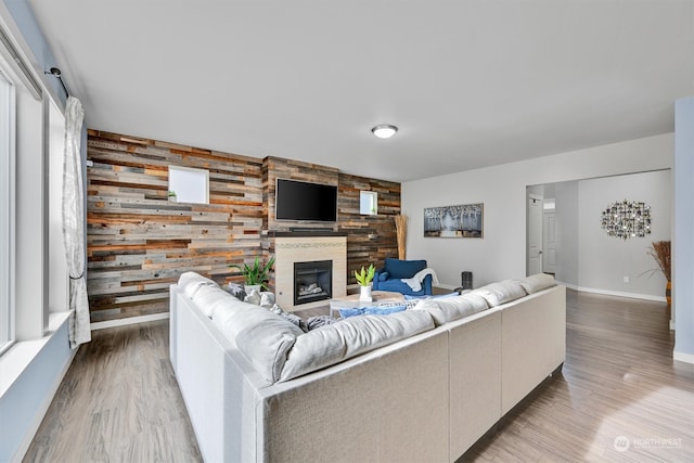 living room featuring plenty of natural light, a fireplace, hardwood / wood-style flooring, and wood walls