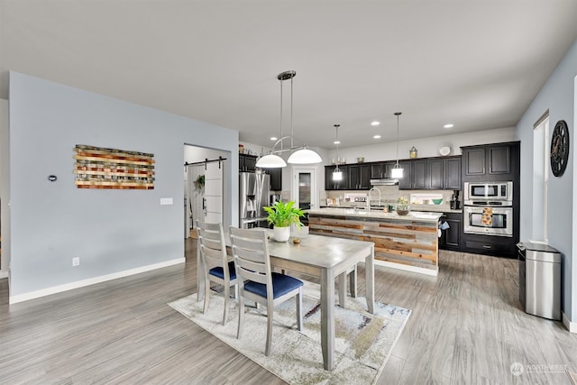 dining area featuring light hardwood / wood-style floors, a barn door, and sink