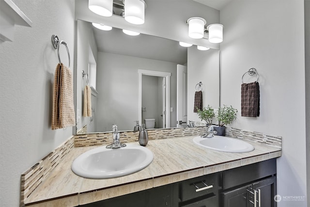 bathroom featuring backsplash, vanity, and toilet