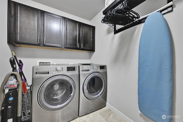 laundry area featuring light tile patterned floors, cabinets, and washing machine and clothes dryer