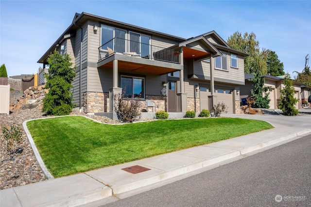 view of front of home featuring a garage, a front yard, and a balcony