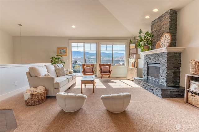 living room with light colored carpet, vaulted ceiling, a mountain view, and a fireplace