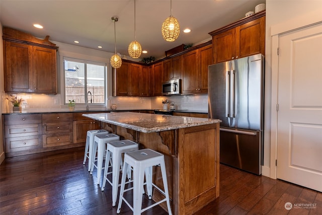 kitchen with a center island, pendant lighting, dark hardwood / wood-style floors, and stainless steel appliances