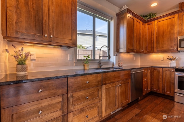 kitchen featuring dark wood-type flooring, sink, decorative backsplash, and appliances with stainless steel finishes