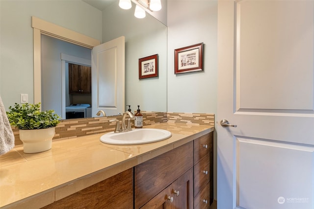 bathroom featuring decorative backsplash, vanity, and independent washer and dryer