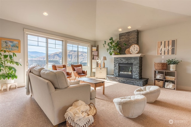 carpeted living room with a mountain view, a stone fireplace, and lofted ceiling