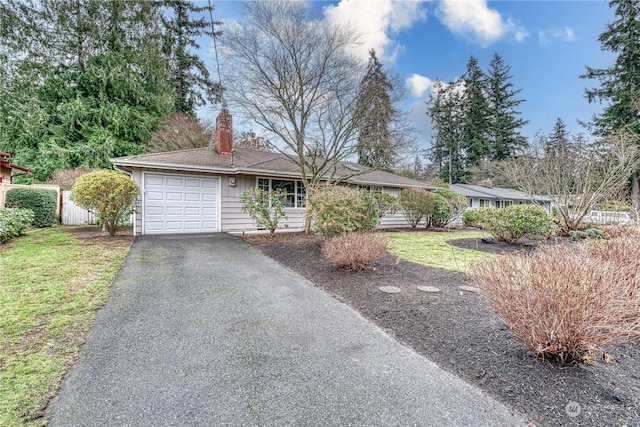 ranch-style house featuring a chimney, fence, a garage, driveway, and a front lawn