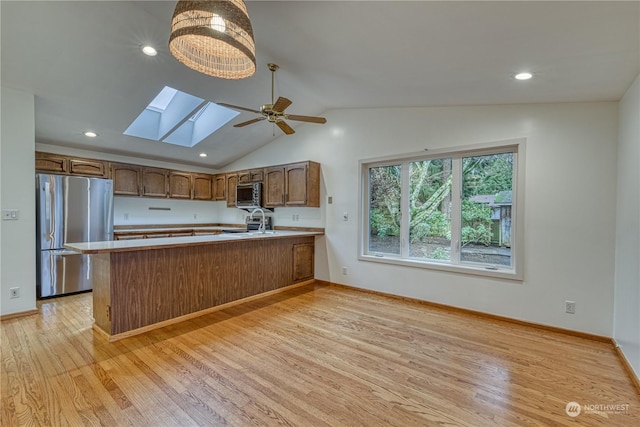 kitchen with a peninsula, brown cabinets, stainless steel appliances, and light countertops