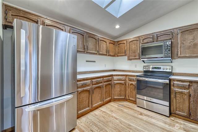 kitchen featuring light wood finished floors, lofted ceiling with skylight, appliances with stainless steel finishes, light countertops, and recessed lighting