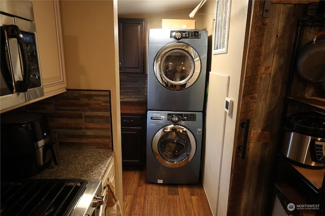 laundry room with stacked washer and dryer and dark wood-type flooring