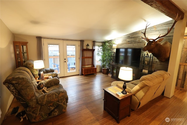 living room featuring wood walls, french doors, vaulted ceiling, and wood-type flooring