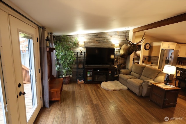 living room with lofted ceiling with beams, hardwood / wood-style flooring, and a large fireplace