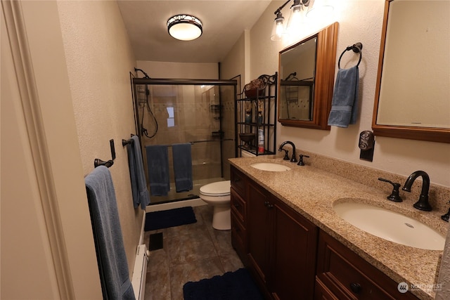 bathroom featuring tile patterned floors, toilet, baseboard heating, vanity, and a shower with shower door