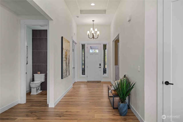 foyer featuring hardwood / wood-style flooring, a chandelier, and a raised ceiling