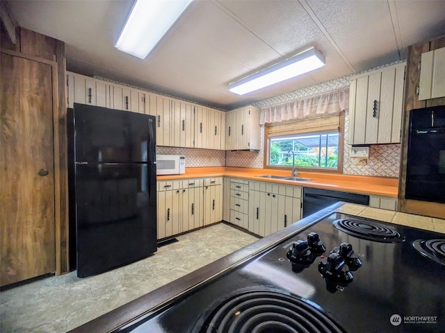 kitchen with black appliances, tasteful backsplash, sink, and cream cabinets