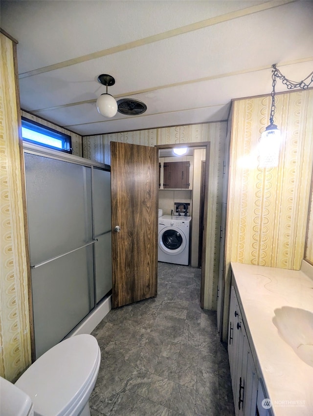 bathroom with toilet, washer / clothes dryer, vanity, and a shower with door