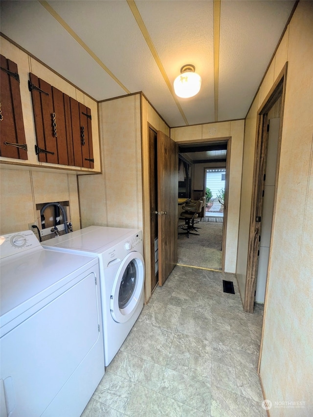 clothes washing area featuring cabinets, a textured ceiling, and separate washer and dryer