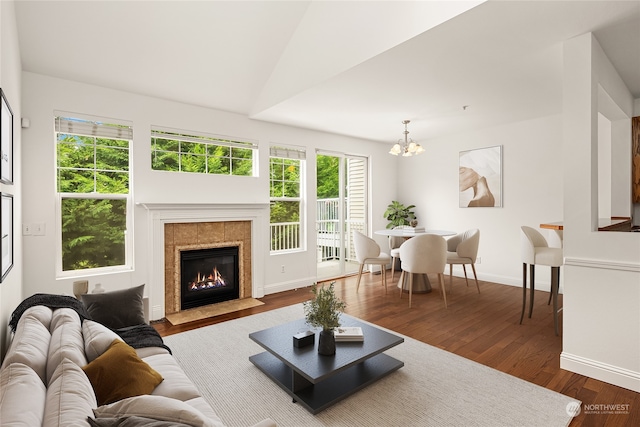 living room featuring lofted ceiling, hardwood / wood-style floors, a fireplace, and a chandelier