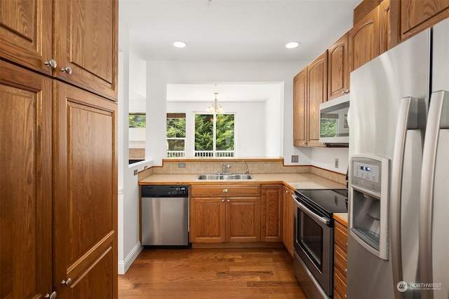 kitchen with sink, appliances with stainless steel finishes, dark hardwood / wood-style floors, and a chandelier