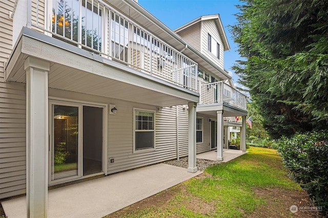 rear view of house featuring a balcony, a yard, and a patio