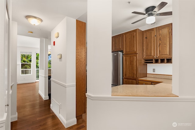 kitchen featuring kitchen peninsula, dark hardwood / wood-style floors, ceiling fan, and stainless steel refrigerator