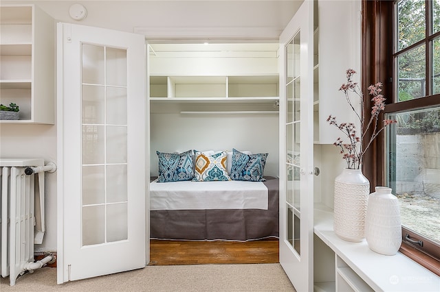 bedroom featuring radiator heating unit, french doors, and light hardwood / wood-style flooring