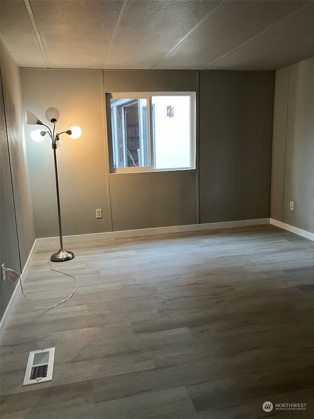 unfurnished room with a textured ceiling and wood-type flooring