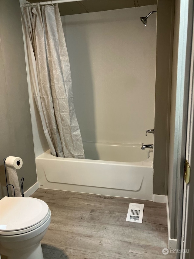 bathroom with toilet, shower / bath combination with curtain, and hardwood / wood-style floors