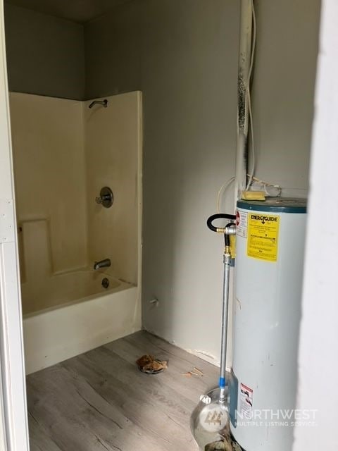 bathroom featuring water heater, hardwood / wood-style flooring, and bathtub / shower combination