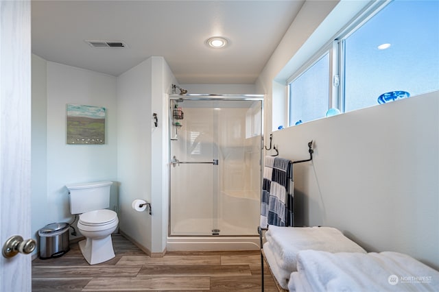 bathroom featuring a shower with shower door, wood-type flooring, and toilet