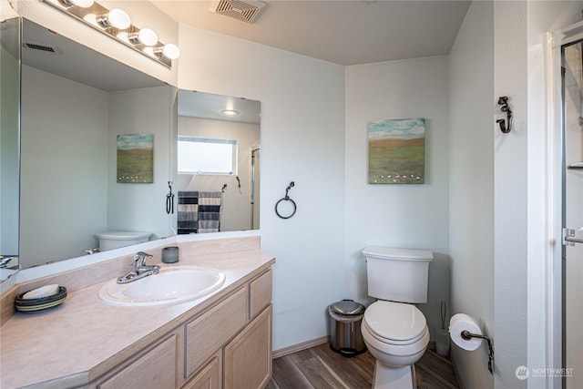 full bath featuring toilet, wood finished floors, vanity, a shower, and baseboards