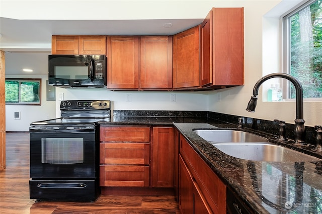 kitchen featuring dark wood-type flooring, dark stone counters, sink, and black appliances