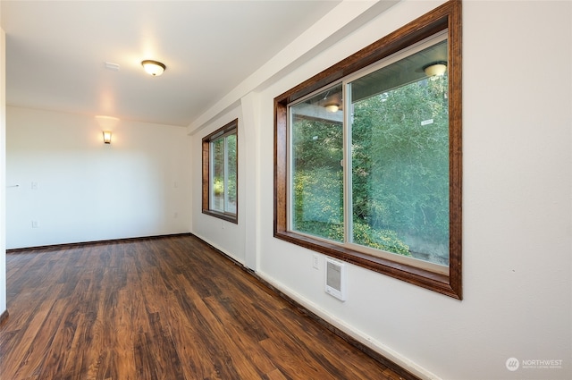 unfurnished room featuring dark hardwood / wood-style flooring and heating unit